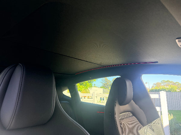 Closed electric roof sunshade installed in a Tesla Model Y Juniper, with LED ambient lighting above the seats.