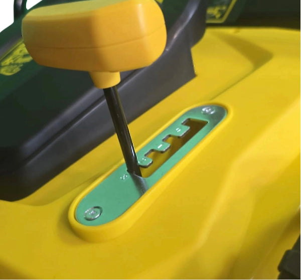 Close-up of a yellow and green lawn mower with a height adjsutment slot.