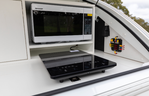 Induction Cooktop and microwave in place in kitchenette area on Little Guy Camper at My Tesla Accessoriess