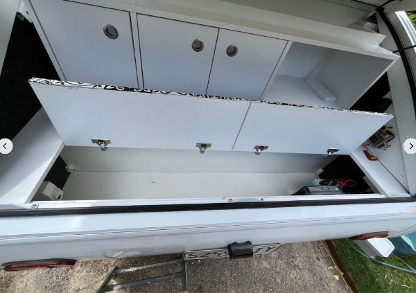 White utility storage cabinets on little Guy camper and a lower storage compartment opened in the back. 