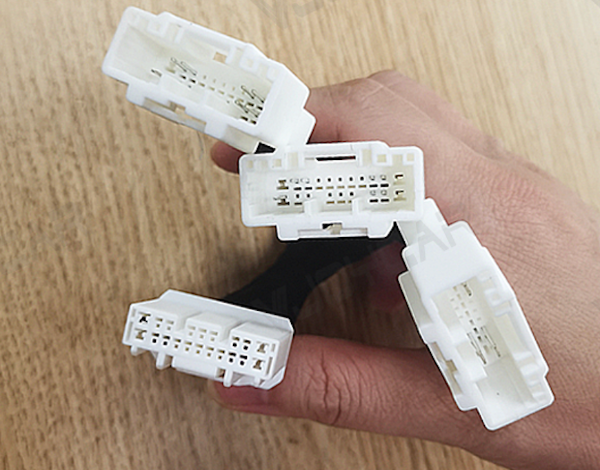 Hand holding four white Tesla AMD CAN Socket One-to-Three Adapters plugs 